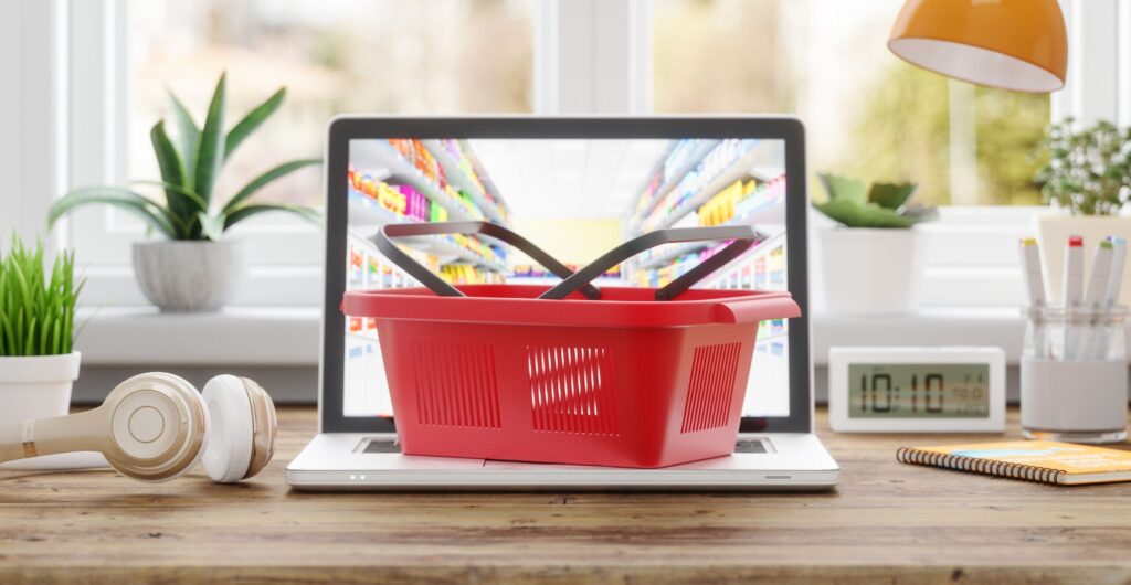 Roter Einkaufskorb auf einem Laptop-Bildschirm mit Supermarktregal-Motiv - Insight zum Online-Lebensmittelhandel