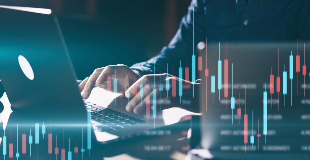 Person tippt auf einem Laptop, überlagert von einem Candlestick-Börsenchart - Insight zum Tempo im Unternehmen