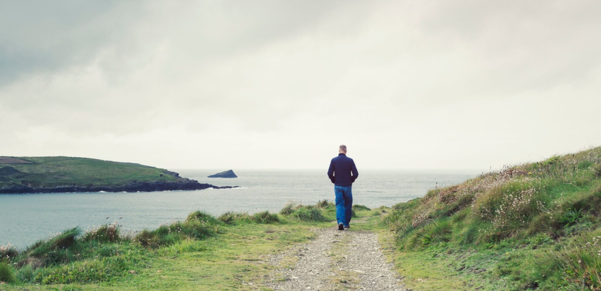 Person die am Meer in einer Duenenlandschaft spaziert als Sinnbild fuer agiles Management