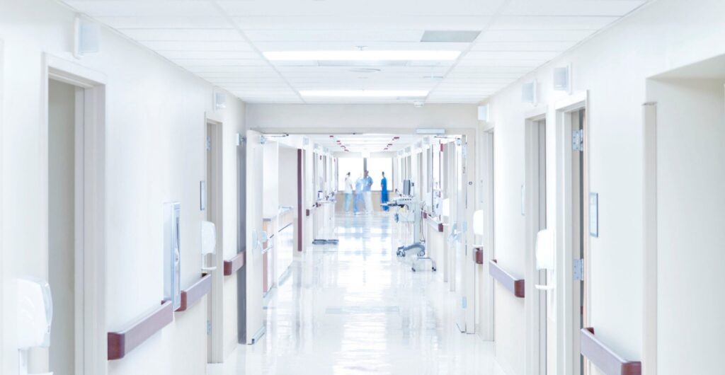 Langer, hell beleuchteter Krankenhausflur mit Pflegepersonal im Hintergrund - Erfolgs-Projekt im Gesundheitswesen