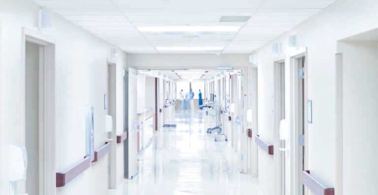 Langer, hell beleuchteter Krankenhausflur mit Pflegepersonal im Hintergrund - Erfolgs-Projekt im Gesundheitswesen