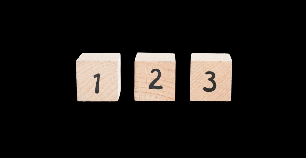 Drei Holzwürfel mit den Ziffern 1, 2 und 3 vor schwarzem Hintergrund - Insight zur Kundenbindung durch Omni-Channel-Management