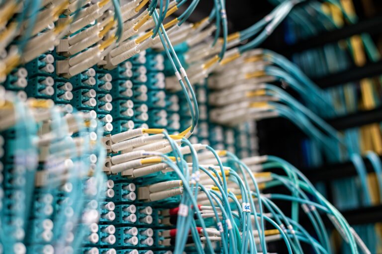 Nahaufnahme eines Glasfaser-Patchpanels mit türkisfarbenen Netzwerkkabeln - Erfolgs-Projekt in der Industrie bei mpcg