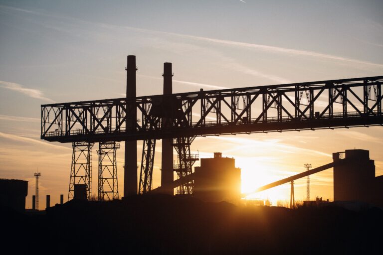 Silhouette einer Industrieanlage mit Kran und Schornsteinen - Erfolgs-Projekt im Dienstleistungssektor bei mpcg